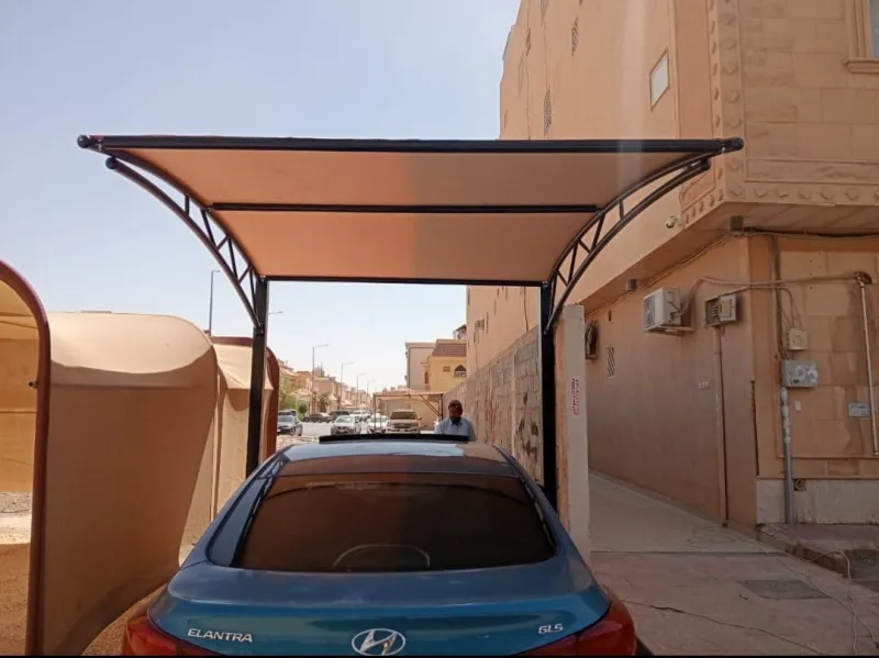 حداد مظلات سيارات يقوم بتفصيل ولحام الهيكل الحديدي للمظلة بدقة وعناية