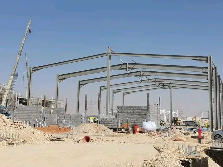 عمال يقومون بتركيب هيكل حديدي لهنجر باستخدام رافعات